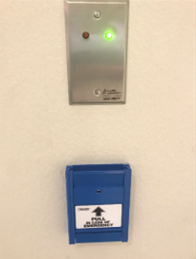 Metal panel at top of image with a small red and green light on it with the green light lit, and a blue lever panel is below metal panel with the pull lever pulled to the disengaged position.