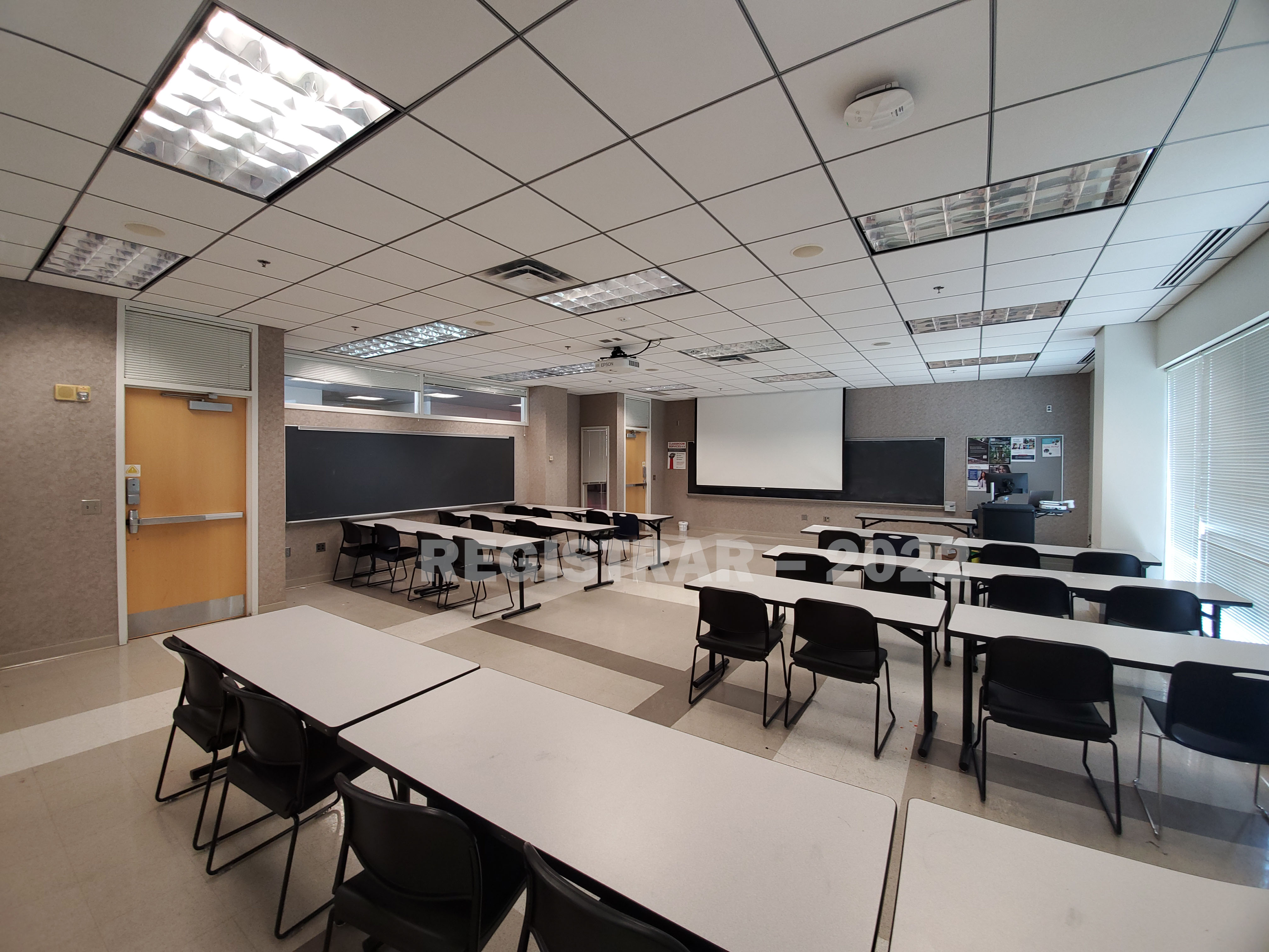 Physical Activity and Education Services Building room 105 ultra wide angle view from the back of the room with projector screen down