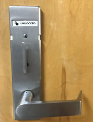Metal lever door handle with thumb-turn lock turned vertically and shown unlocked attached to a wooden door