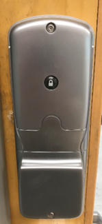 Internal view of metal door lock with rubber door lock button in the middle, attached to wooden door