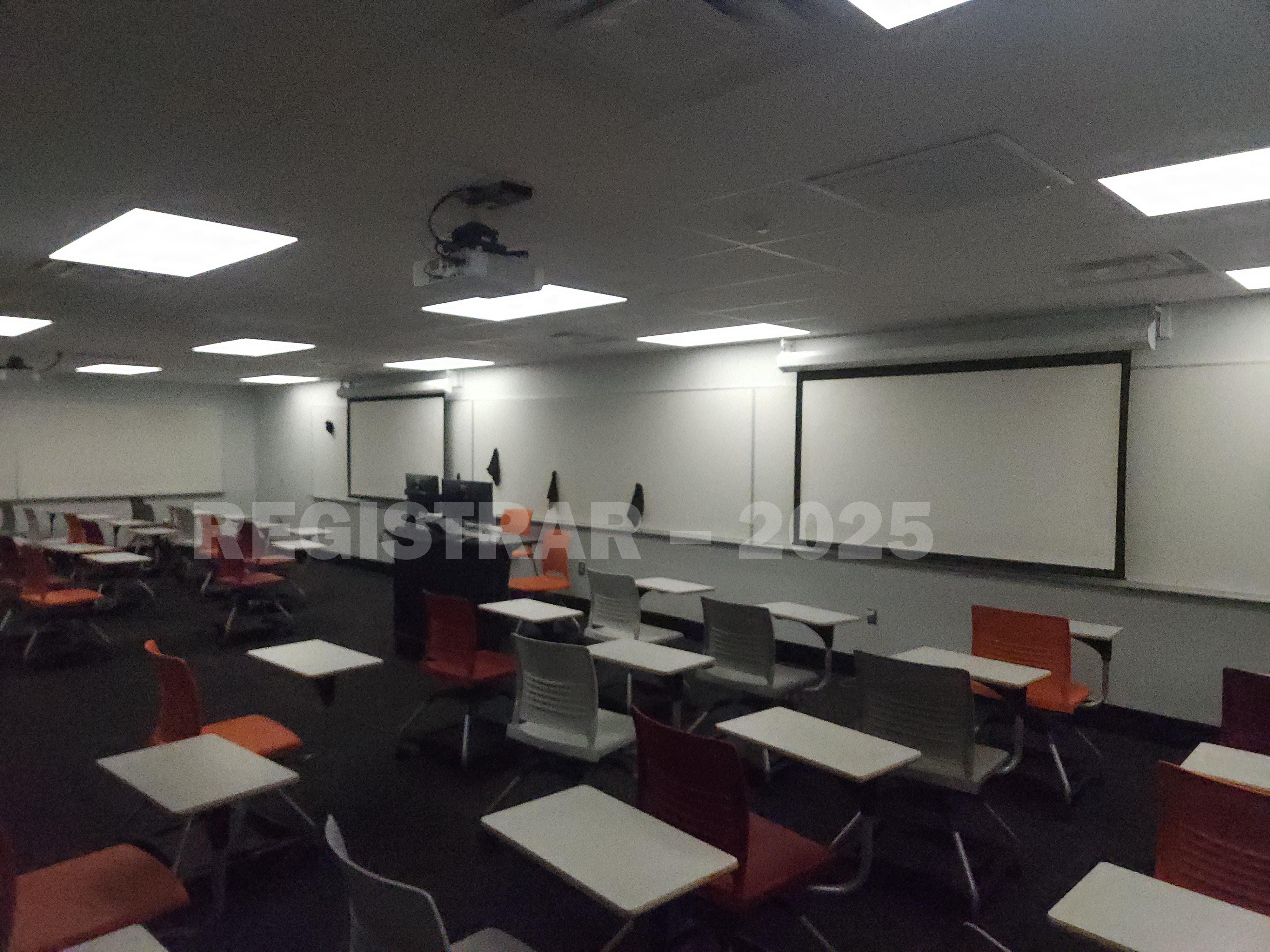 Journalism Building room 221 view from the back of the room with projector screen down